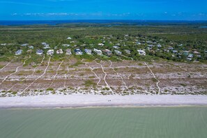 Vue aérienne d’une zone résidentielle côtière, avec des maisons, des routes et une plage.