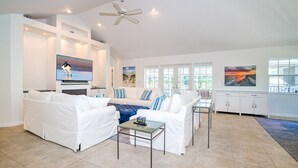 A spacious living room with white sofas, a glass coffee table, and artwork on the walls. - Spacious Single Family Home "Breaking Away" Steps from the Beach (Sanibel)