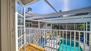 A covered outdoor area with a pool, wooden deck, and a view of a house. - Spacious Single Family Home "Breaking Away" Steps from the Beach (Sanibel)