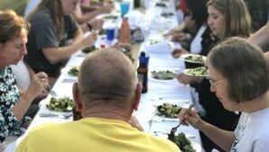 A group of people seated at a long table with plates of food, suggesting a communal dining setting. - Good Place Farms Upper Barn (Lexington)