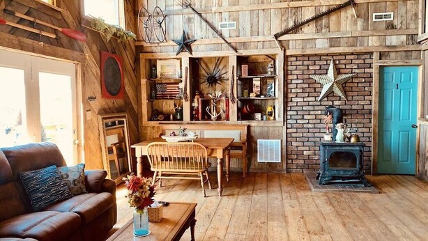 A rustic interior with wooden walls, a fireplace, and a dining area. - Good Place Farms Upper Barn (Lexington)