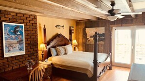 A bedroom with a four-poster bed, a desk with a chair, a large window, and a ceiling fan. - Good Place Farms Upper Barn (Lexington)