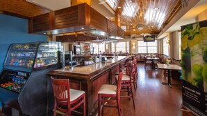 Un ristorante con arredi in legno, una zona bar e un bancone con sgabelli.