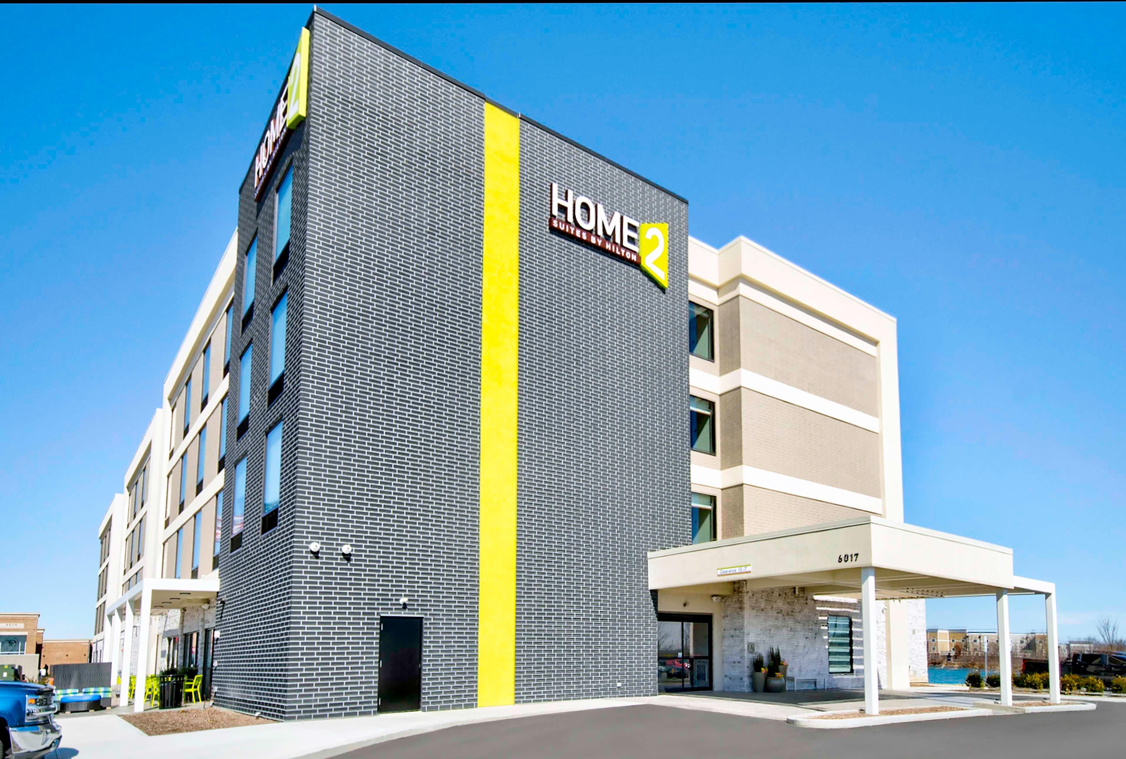 Un hôtel moderne, reconnaissable à son grand panneau « HOME 2 », à sa façade en briques et à son entrée abritée.
