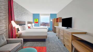 Een hotelkamer met een bed, een bureau, een televisie, een stoel en een raam met uitzicht op de stad.