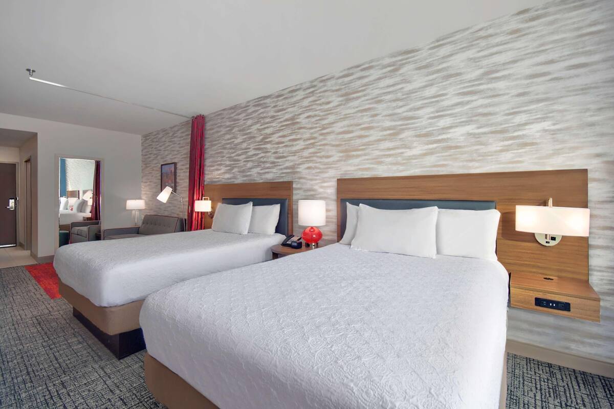 Een hotelkamer met twee bedden, een rode accentmuur en een modern design.