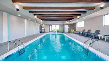 Una piscina con barandillas de metal, vigas de madera en el techo y sillas a un lado.