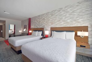 Een hotelkamer met twee bedden, een rode accentmuur en een modern design.