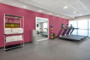 Een sportschool met een loopband, trainingsballen en een handdoekhouder.