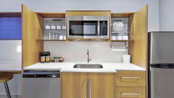 Una cocina moderna con microondas integrado, pileta de acero inoxidable y armarios de madera.