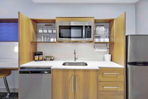 Una cucina moderna con forno a microonde integrato, lavello in acciaio inox e pensili in legno.