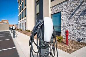 Una stazione di ricarica Tesla con un edificio a facciata in pietra sullo sfondo.