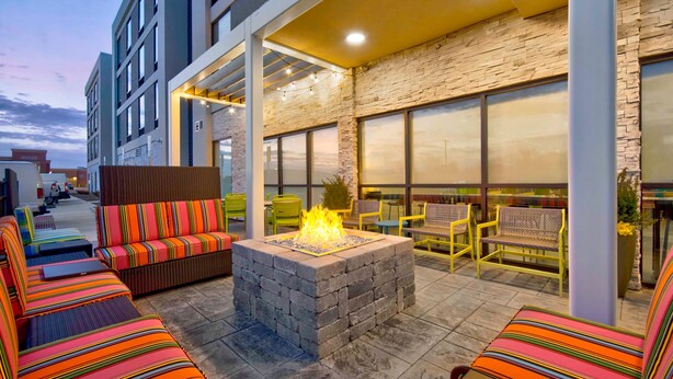 Zona d'estar a l'exterior amb un foc de llar, seients i cadires amb coixins.