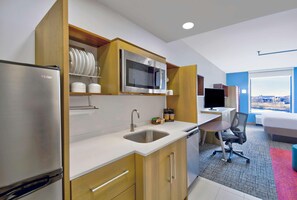 A modern kitchen with a refrigerator, microwave, sink, and wooden cabinets. - Home2 Suites by Hilton Whitestown Indianapolis NW (Whitestown)