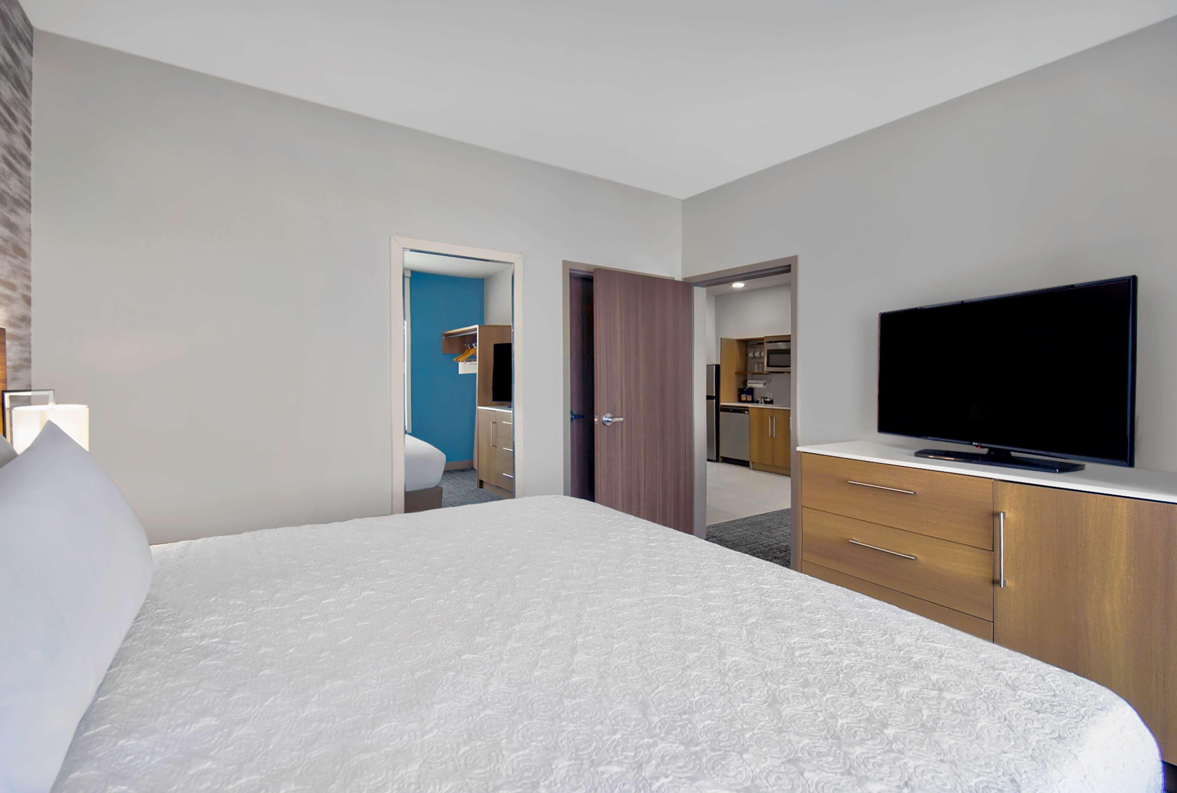 Une chambre d’hôtel avec un grand lit, une télévision, un bureau et une kitchenette.