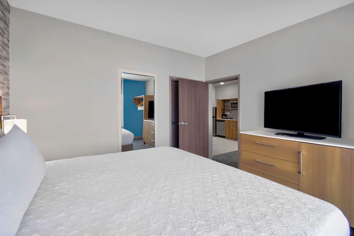 Een hotelkamer met een groot bed, een televisie, een bureau en een kitchenette.