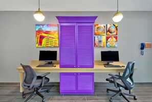 A workspace with two desks, each with a computer and chair, and a central purple cabinet.