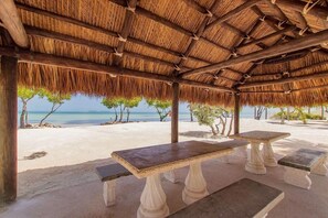 A beachside pavilion with a thatched roof, a table, and benches. - Island pool home awaits in Islamorada's Port Antigua (Islamorada)