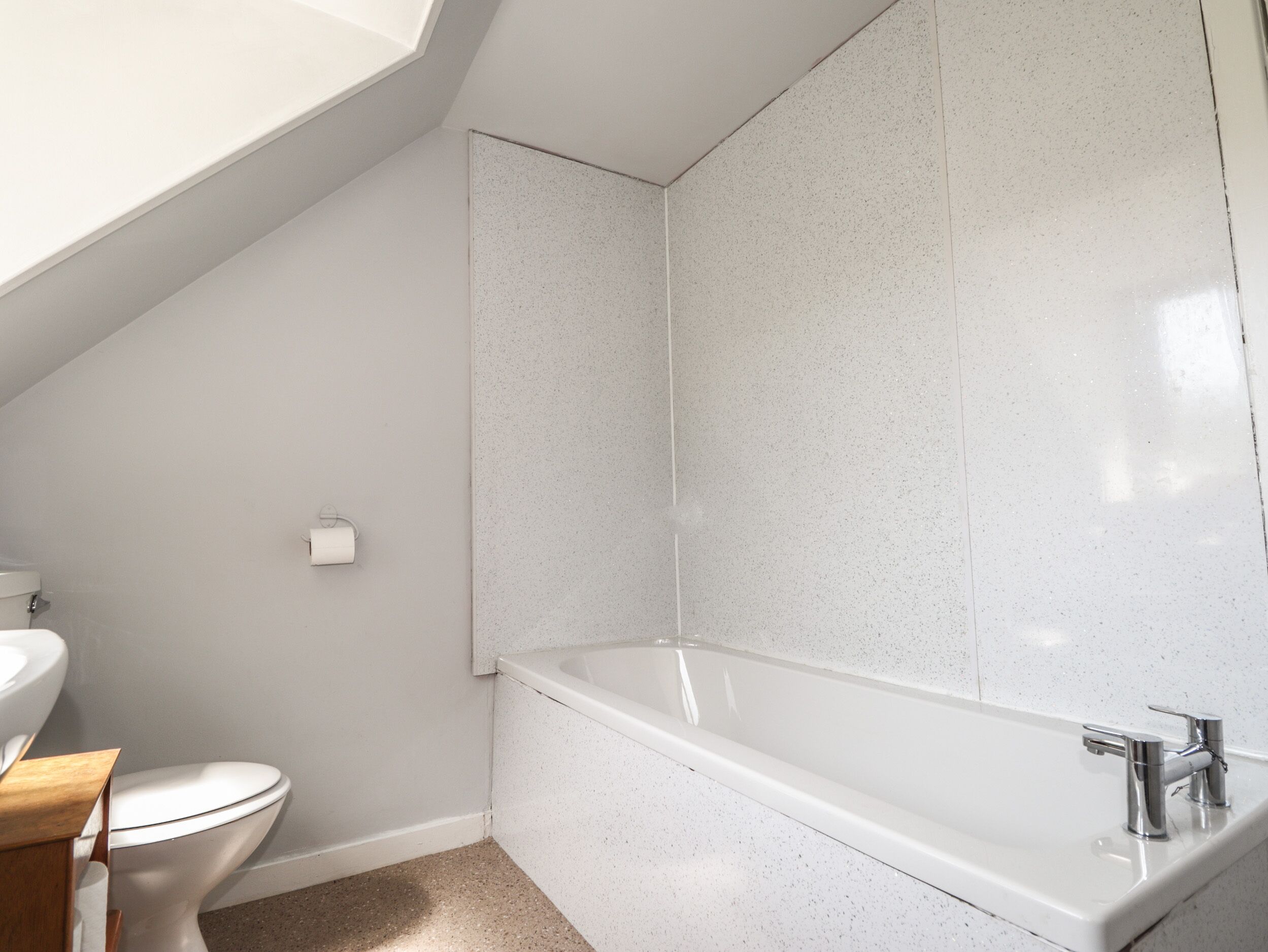 Et badeværelse med toilet, vask og badekar.