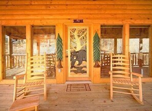 Step into this cozy cabin with a welcoming porch featuring two chairs and a warm entrance.