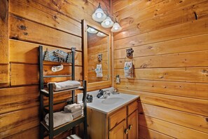 A wooden cabin bathroom with a wooden vanity, a mirror, and a shelf with towels. - 2 bed/2 bath/ loft with game room/pool tables, hot tub... (Sevierville)