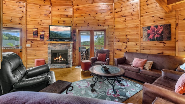Interior acogedor de una cabaña con chimenea, mobiliario de cuero y paredes de madera.