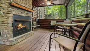 A log cabin interior with a fireplace, wooden deck, and large windows offering a forest view. - 2 Bedroom/2 Bathroom Cabin, PRIVATE! (Sevierville)