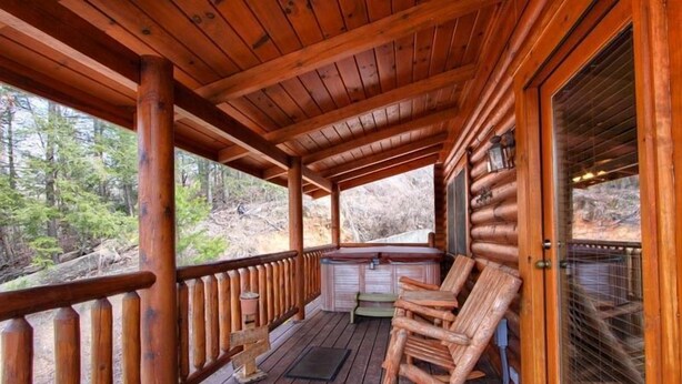 A wooden deck with a rocking chair and a bench, overlooking a forested area. - Romantic Smoky Mountain Retreat with Hot Tub & Pool Table (Sevierville)