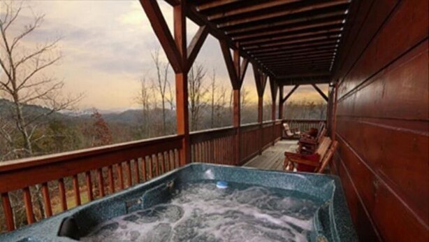 Un jacuzzi con terraza de madera y vistas del paisaje circundante.