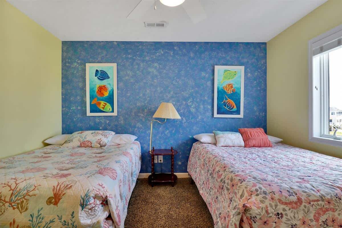 A room with two beds, a lamp, and wall art.