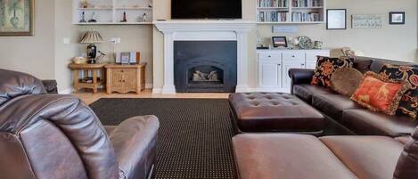 A living room with a fireplace, a television, and a bookshelf.