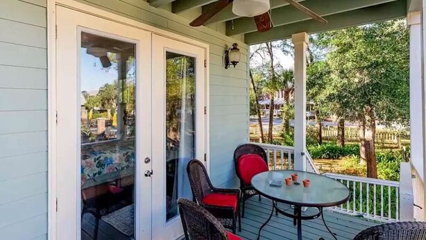 A covered outdoor seating area with wicker chairs and a table, overlooking a garden. - Hatch Life in Steinhatchee Landing (Steinhatchee)