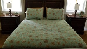 A bed with a floral bedspread, two matching pillows, and two nightstands with lamps and decorative items. - Hatch Life in Steinhatchee Landing (Steinhatchee)
