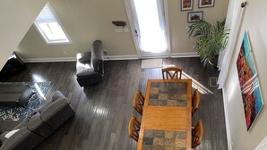 A spacious living area with a dark wood floor, a gray sofa, a recliner, and a wooden dining table with chairs. - Hatch Life in Steinhatchee Landing (Steinhatchee)