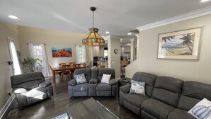 A living room with a sectional sofa, a coffee table, and a dining area with a table and chairs. - Hatch Life in Steinhatchee Landing (Steinhatchee)