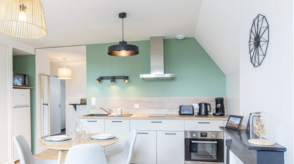 Enjoy cooking in this well-equipped kitchen with a central island, sink, stove, and microwave, as well as a dining area with a table and chairs.