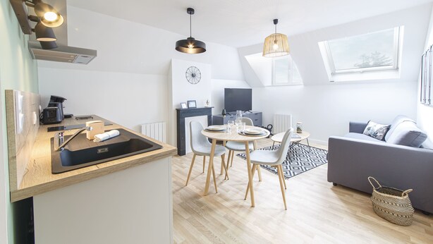 Una cocina moderna con comedor, sofá y televisor.