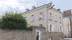 Un edificio de dos pisos con fachada de piedra, varias ventanas y una puerta pequeña.