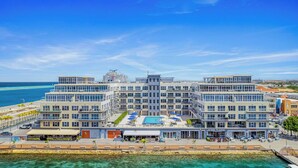 Ein mehrstöckiges Hotel mit Poolbereich, Sitzgelegenheiten im Freien und Blick auf den Ozean.