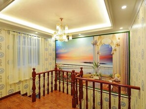 Staircase leads to an upper level, flanked by patterned wallpaper and a vibrant mural.