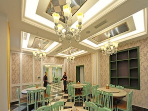 Classic dining area with a checkered floor, green chairs, and a central chandelier.