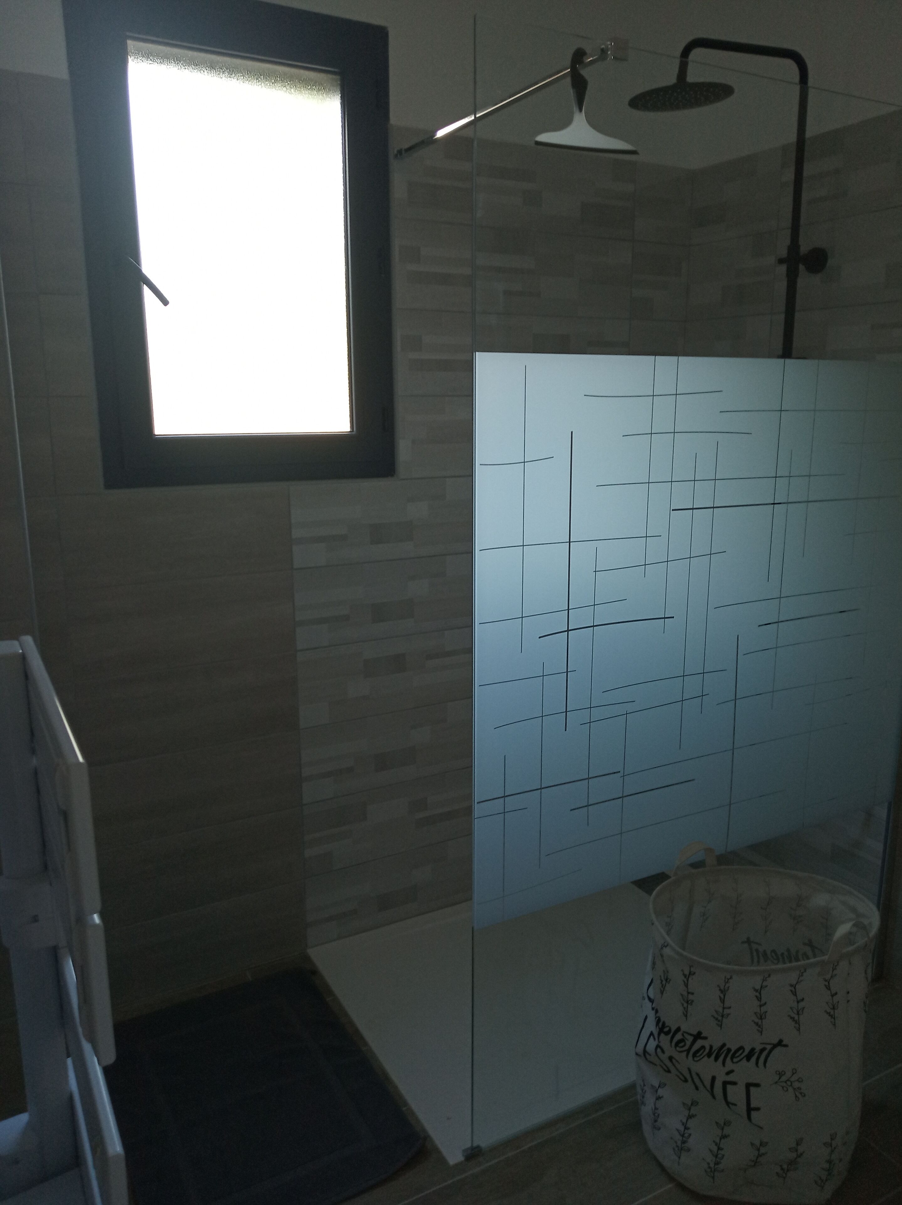 Une salle de bain avec une douche, une fenêtre et un porte-serviettes.