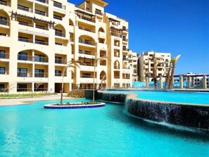 A hotel with multiple balconies, a swimming pool, and a water feature. - Amazing location in hurghada IN Al dau heights (Hurghada)