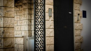 Un muro de piedra con una puerta negra y una reja metálica.