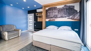 Un dormitorio con una cama, una silla, un armario y un ventanal grande.