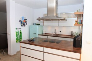 Una cocina moderna con una isla central, extractor de acero inoxidable y microondas integrado.
