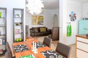 Un comedor con una mesa de madera, sillas y una araña.
