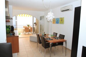 Un comedor con una mesa de madera, sillas negras y una lámpara colgante blanca.
