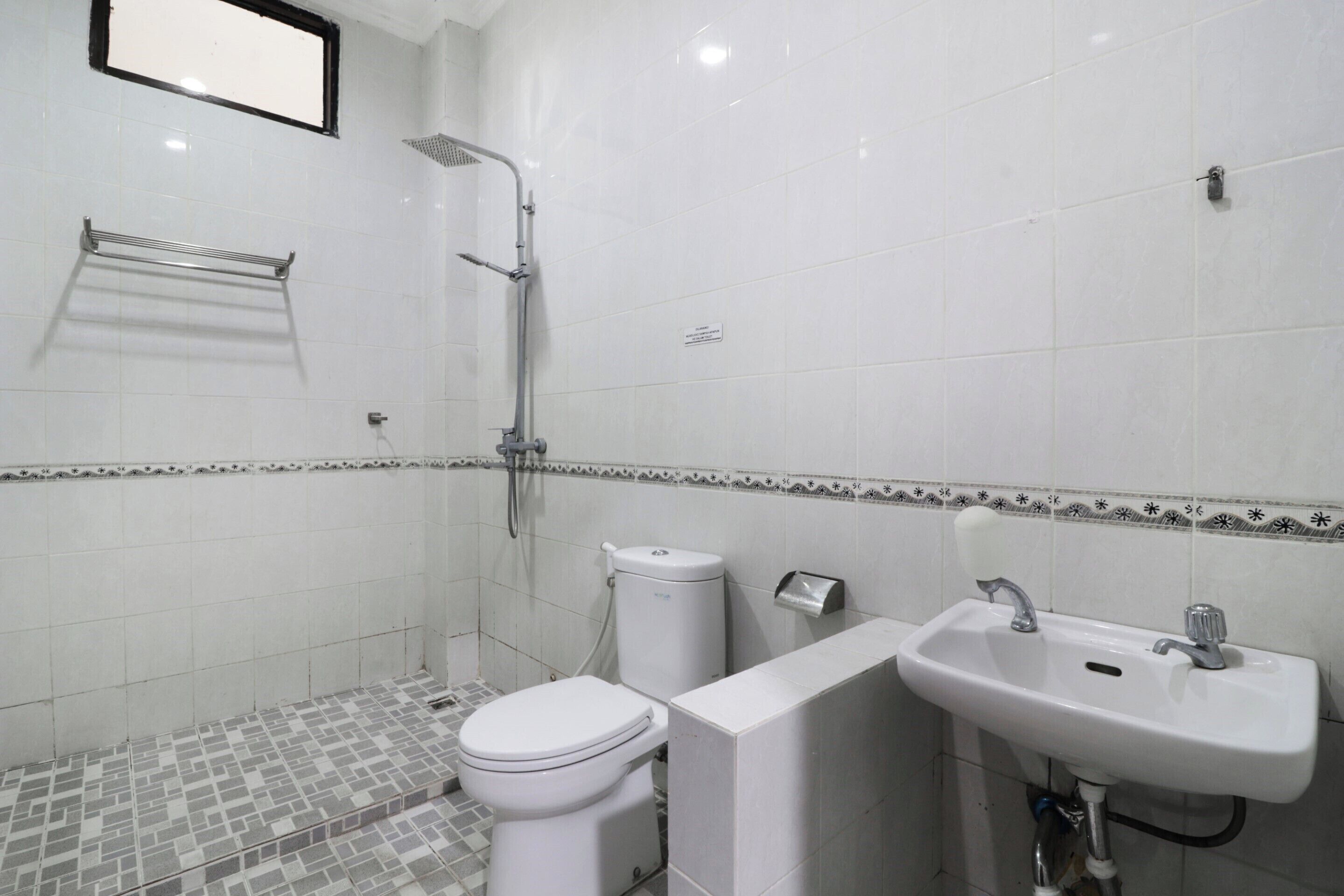 A bathroom with a toilet, shower, and sink.