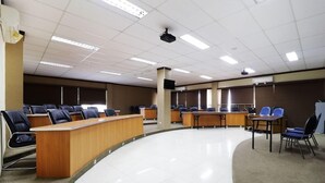 Une salle de conférence à l’agencement incurvé, dotée de plusieurs tables et de chaises.